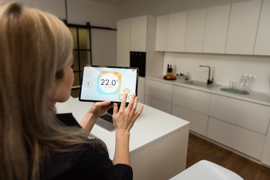 Iot Smart Home Concept - rear view of woman ask digital tablet to set temperature of air conditioner